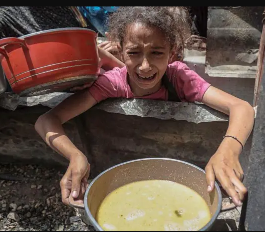 Foto de una niña con una olla pidiendo comida